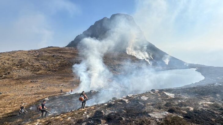 Fire fighters spraying water over the smoky fire on Stac Pollaidh