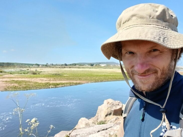 The Scottish Wildlife Trust's Reserves Project Officer for North Scotland, Michael Suender, smiles at the camera beside a river.